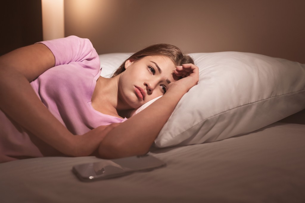 Teenage girl suffering from insomnia while lying in bed at night